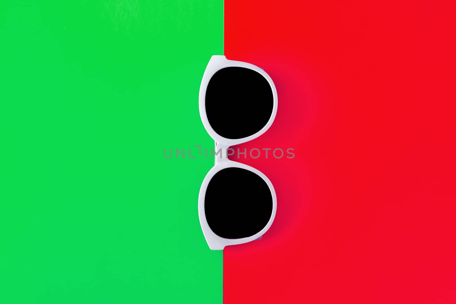 Sunny stylish white sunglasses on a bright green-cyan and red-orange background, top view, isolated. Copy space. Flat lay by Tanacha