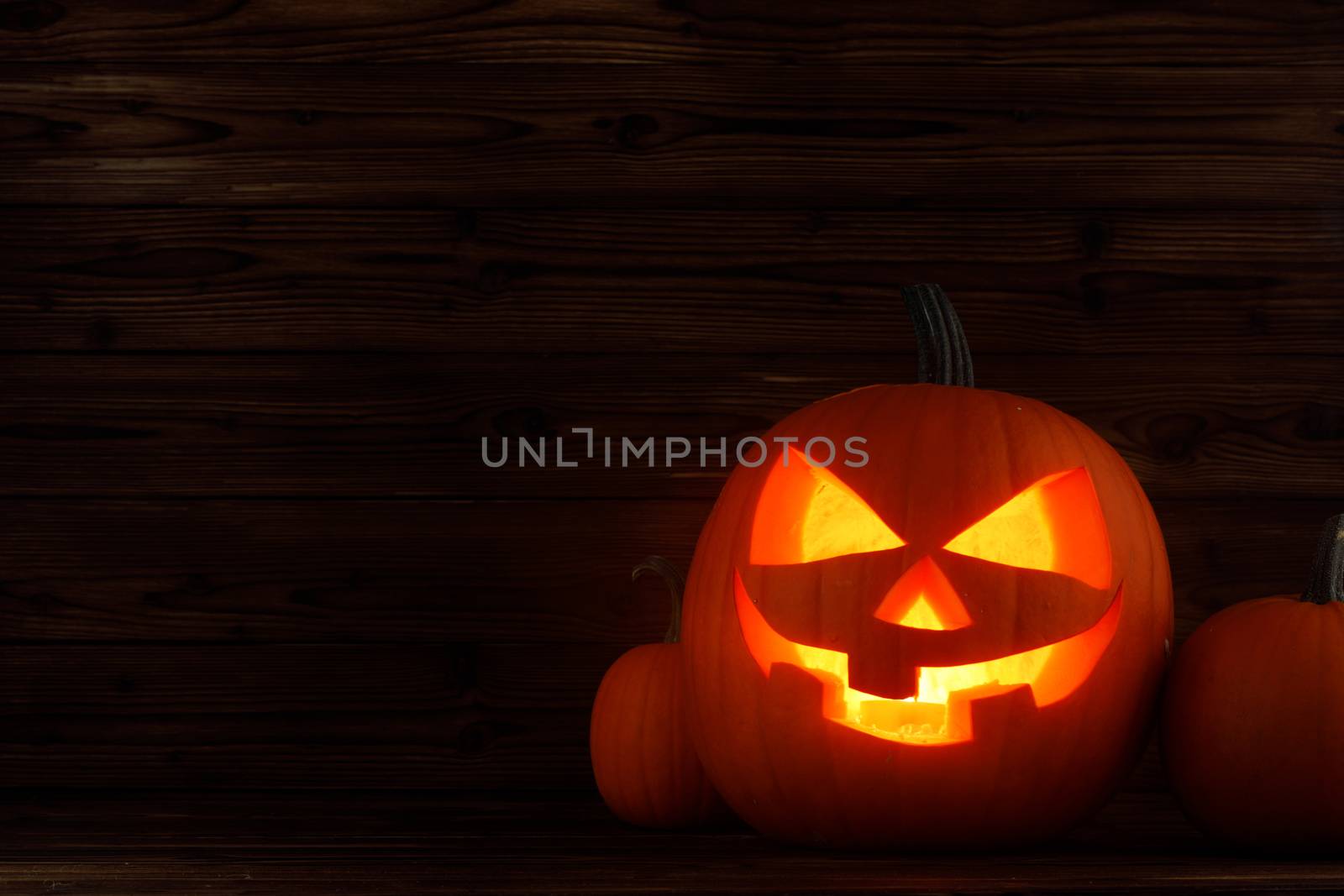 Glowing Halloween pumpkin heads jack o lantern on wooden background