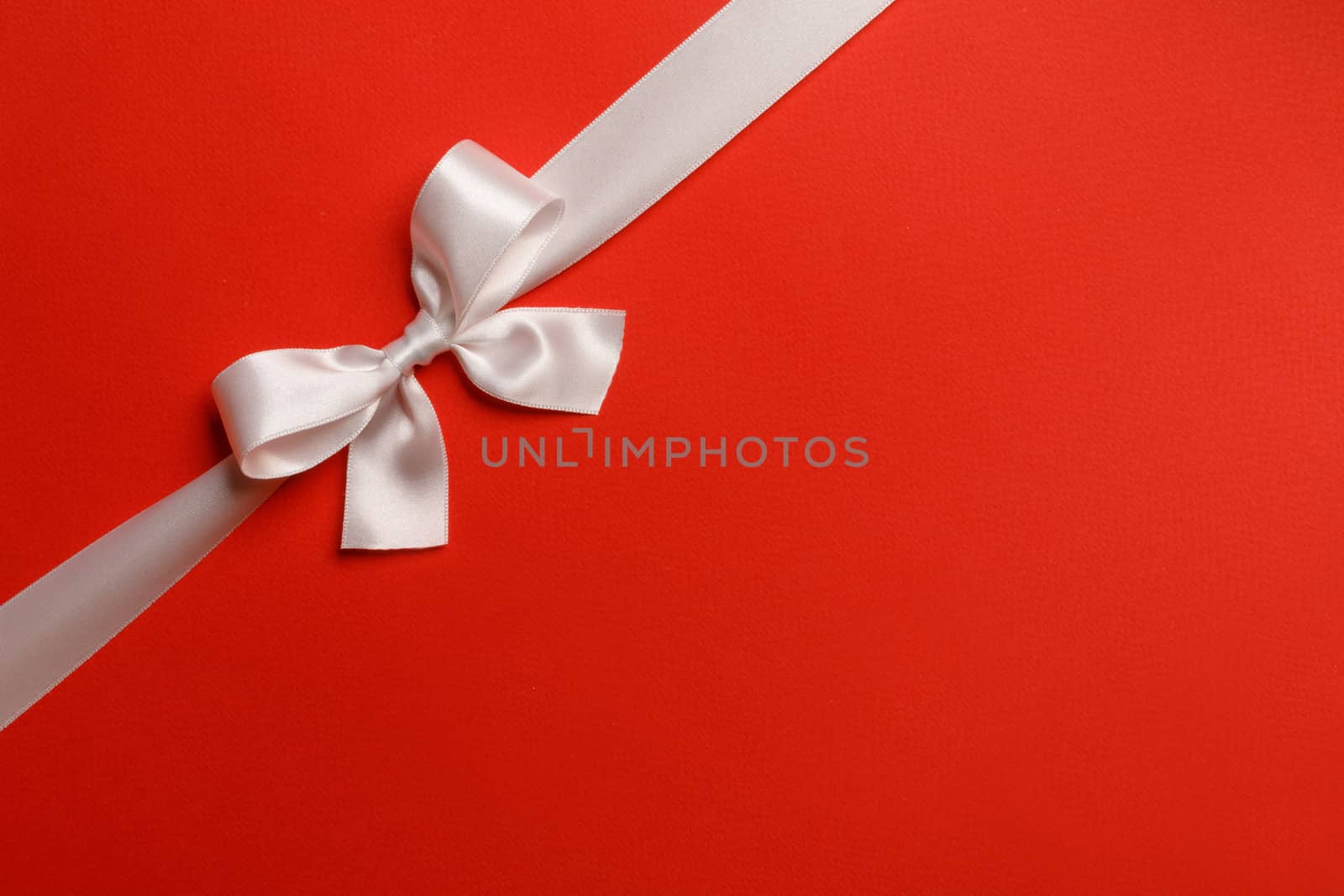 Shiny white satin ribbon and bow on red background. Holiday gift concept