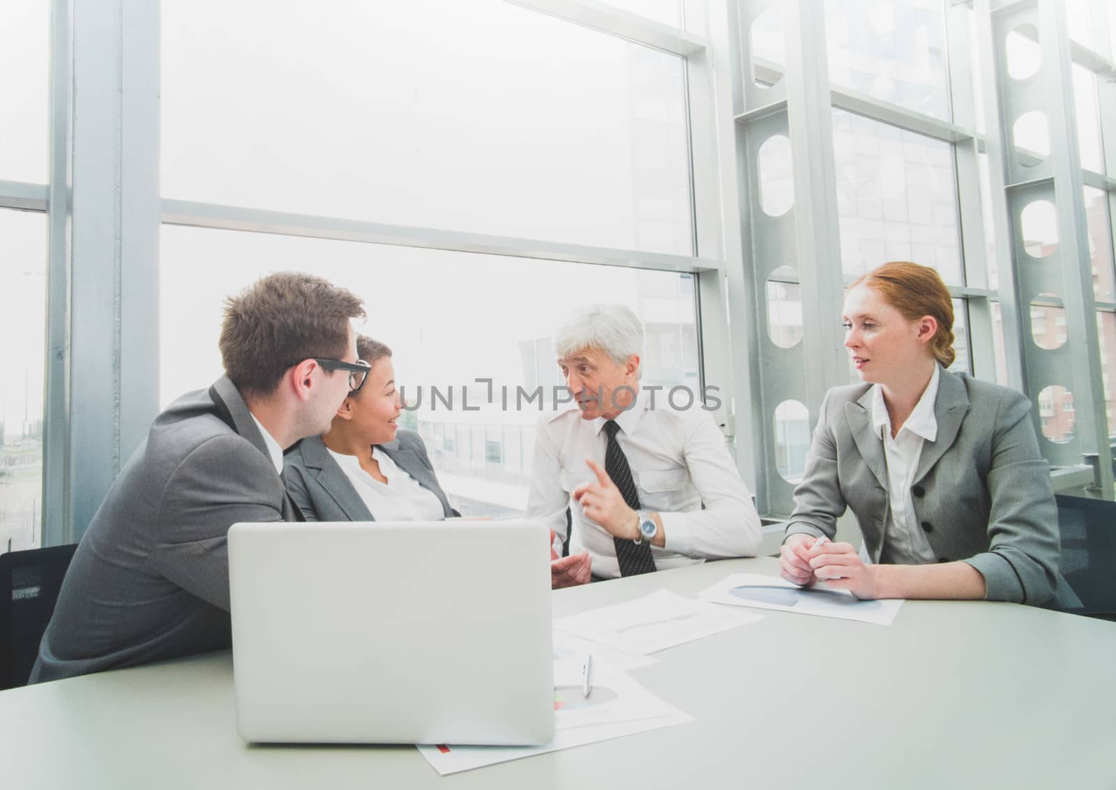 Business team sitting by the table with laptop and documents in office