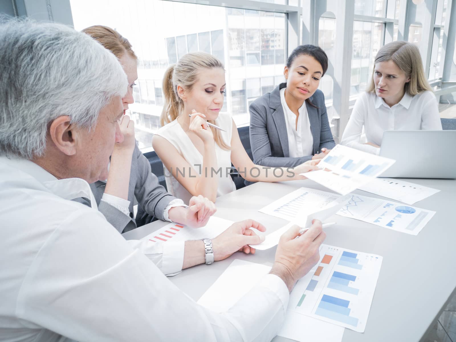 Group of business people discussing diagrams in office together