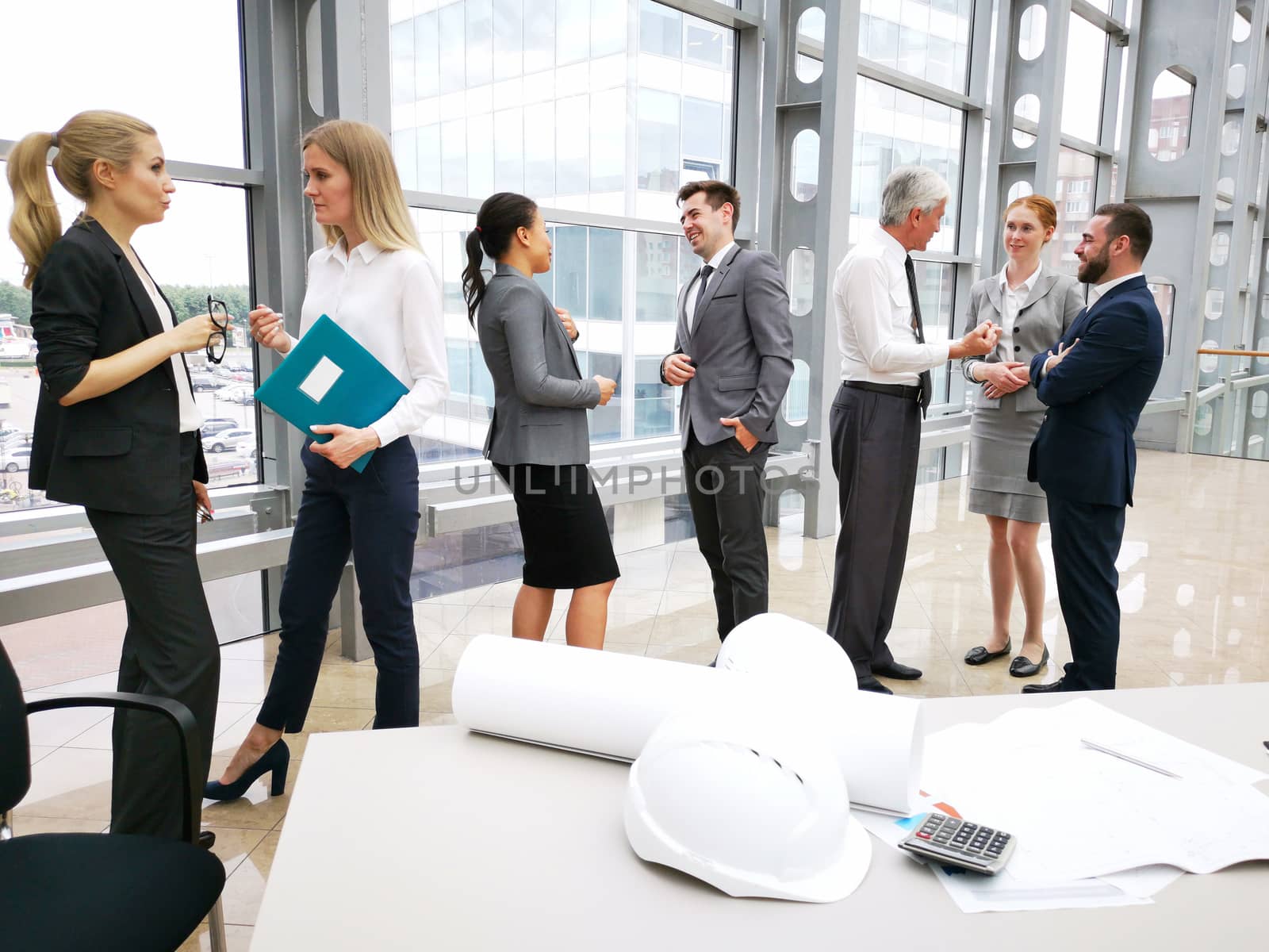 Business people team discuss construction issues , hardhat , blueprint , contract , documents , calculator on office table