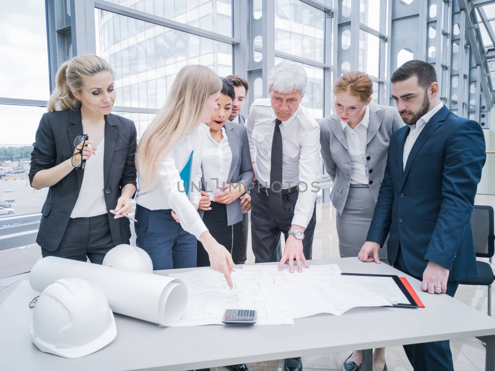 Business people team discuss construction issues , hardhat , blueprint , contract , documents , calculator on office table