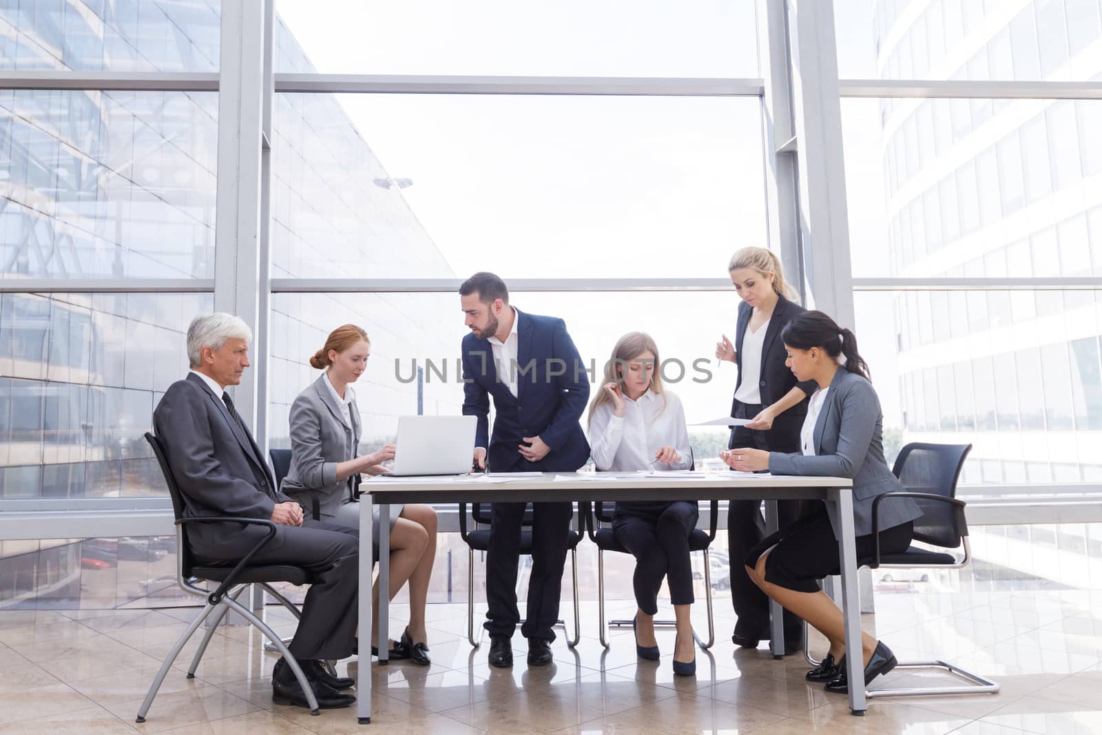 Business team sitting by the table with laptop and documents in office