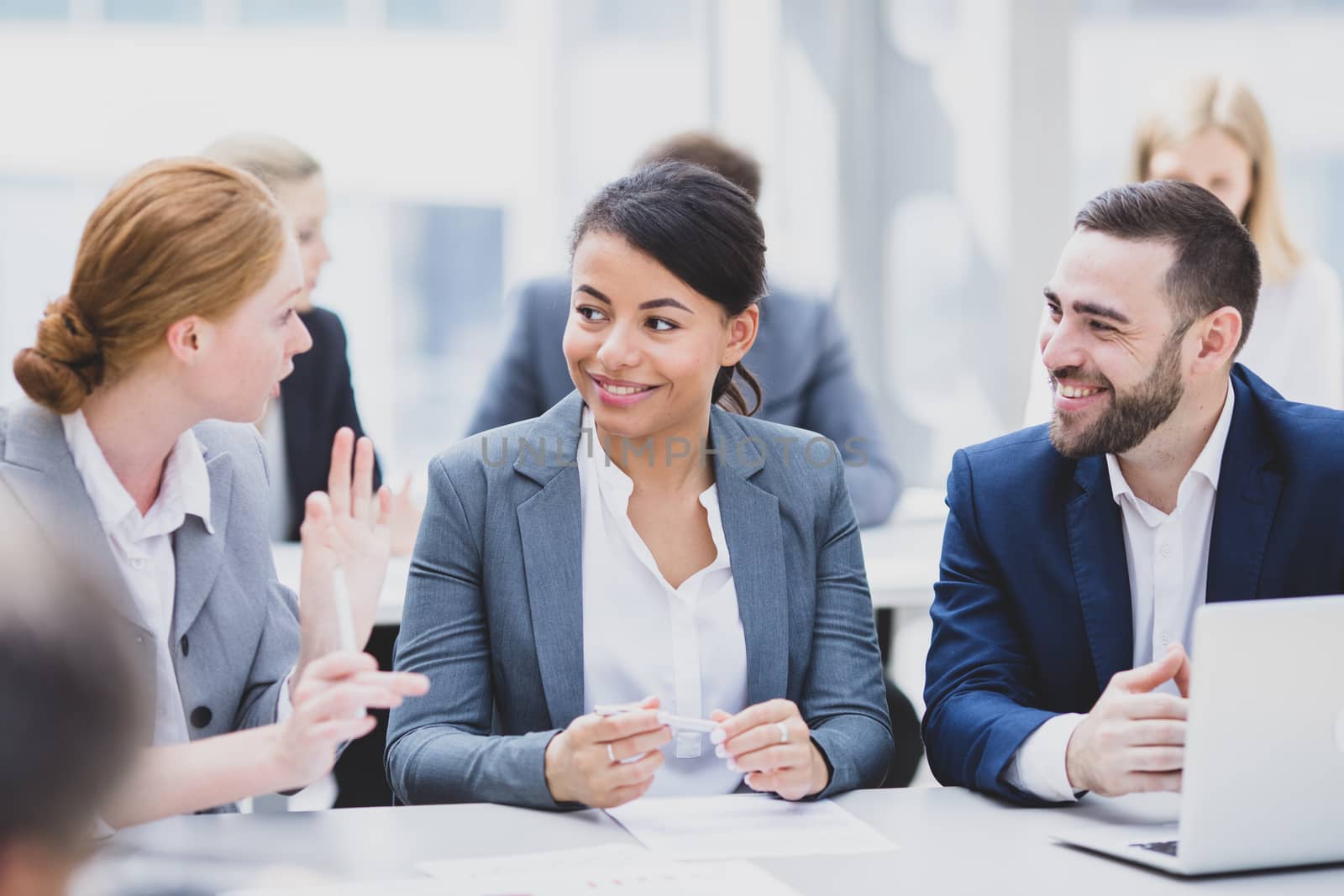 Business team sitting by the table with laptop and documents in office