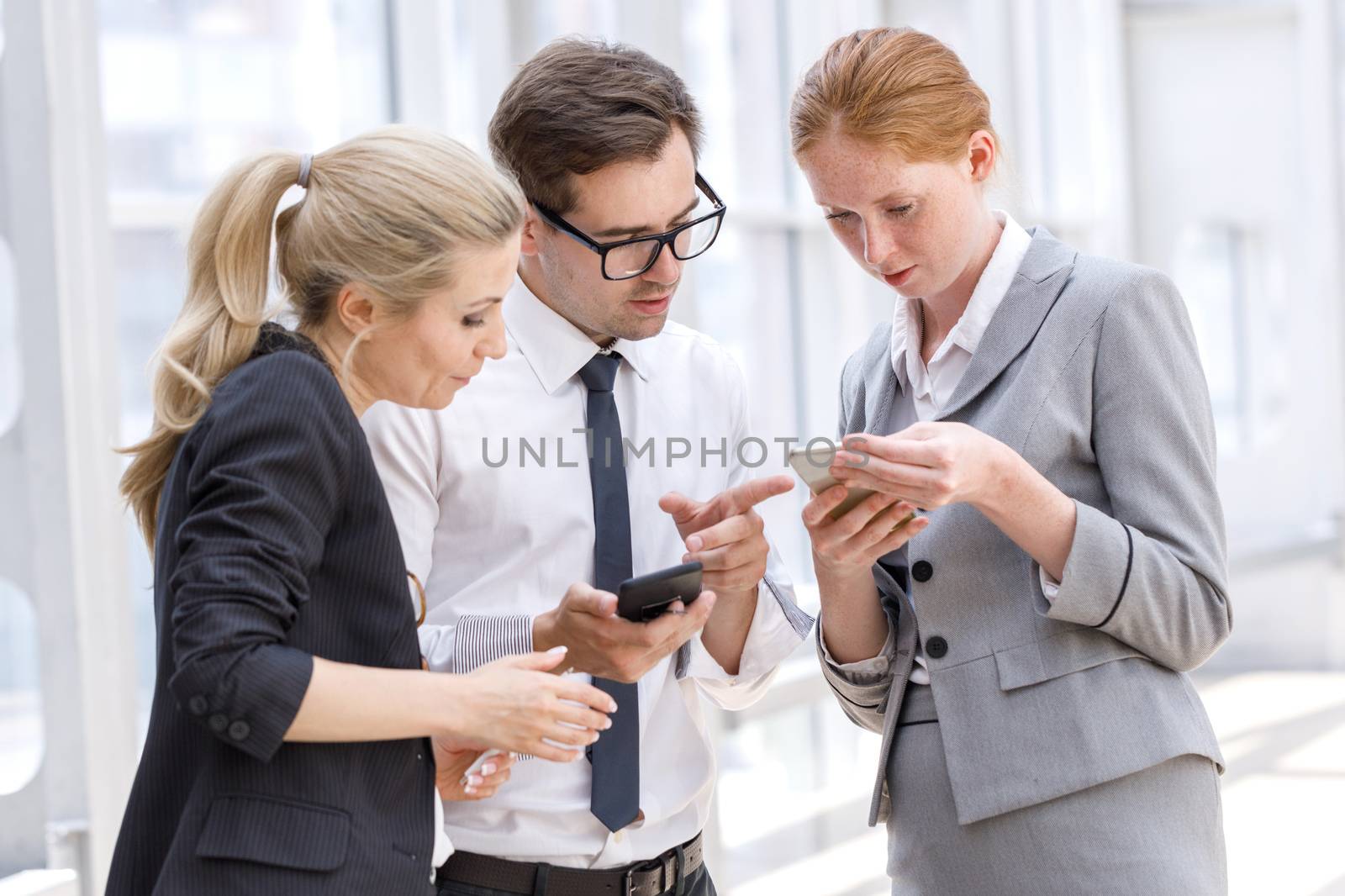 Business people with mobile phones surfing the net at break in office