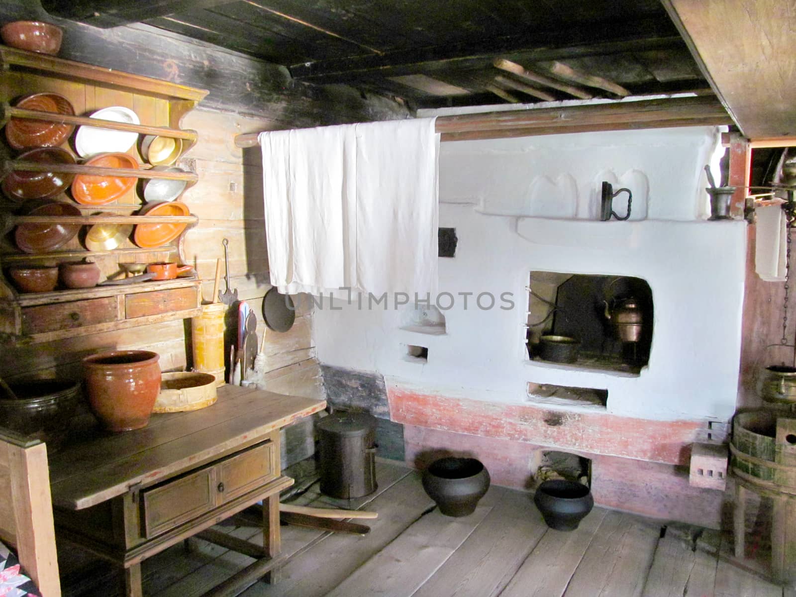 Russian stove with attributes of the last century in the foreground 
such as iron, 
tub, clay jugs, plates and cups made of clay,
cast iron and other dining utensils.
