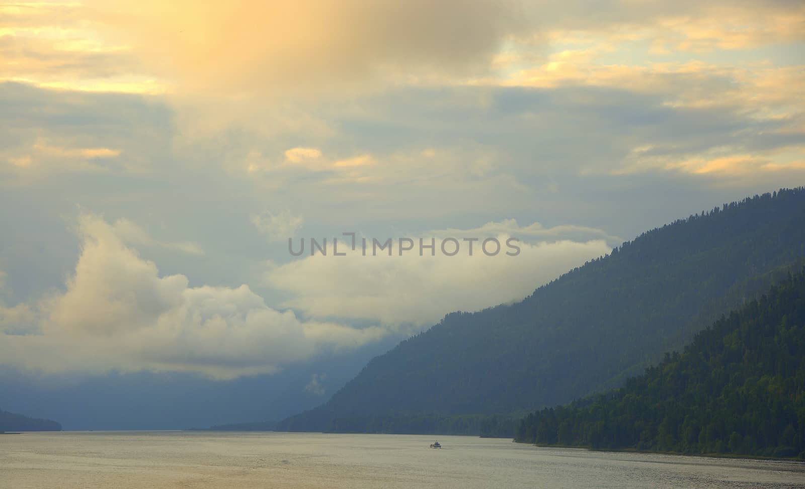 Morning on a mountain lake, clouds descend to the water, overcast. Altai, Siberia, Russia