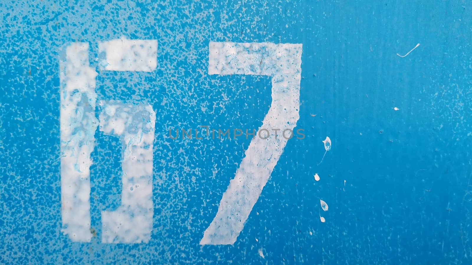 The number 67 with white paint on a cracked blue background.