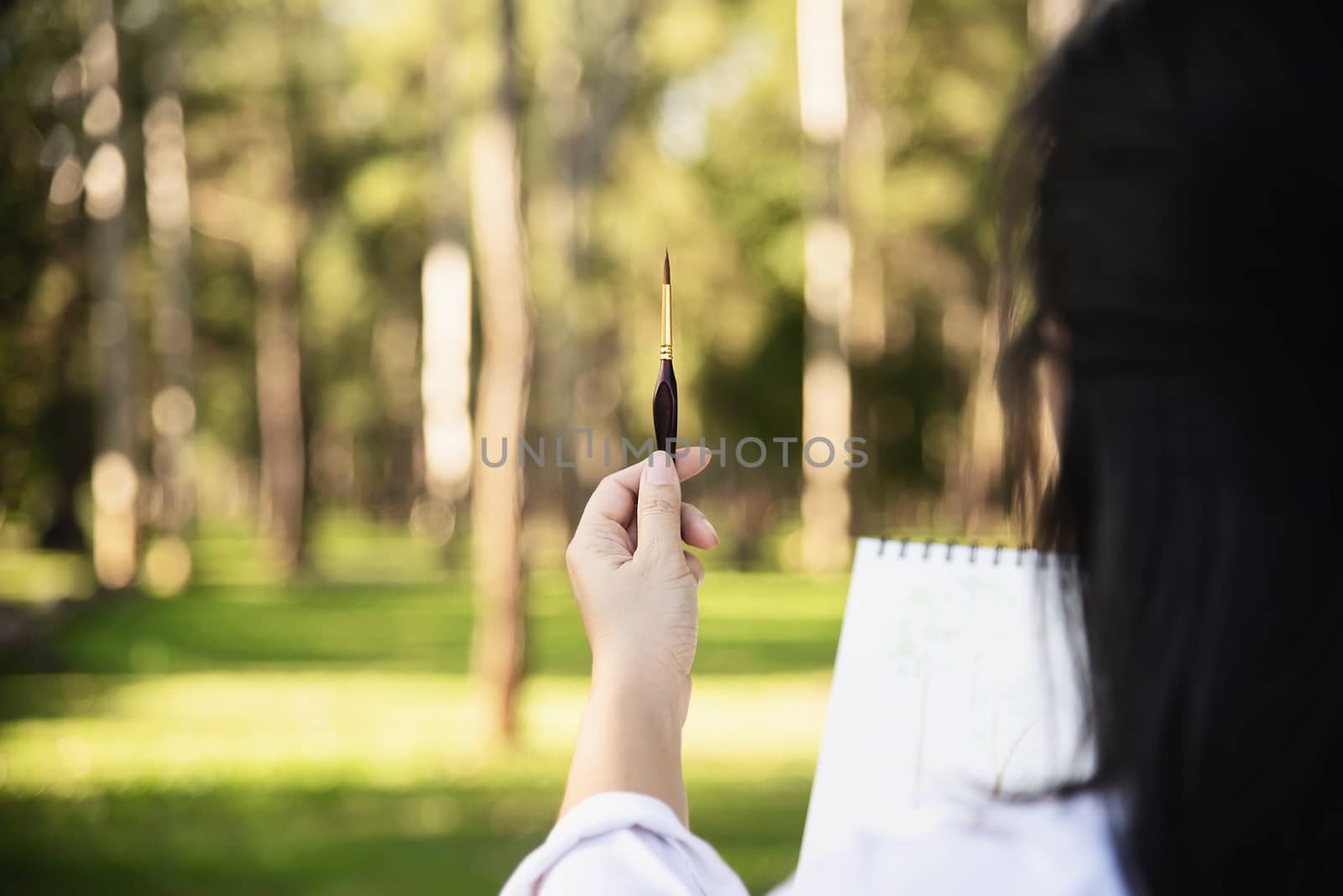 Relax woman painting water colour art work in green garden forest nature - people with creative art in nature stress reduction and meditation concept