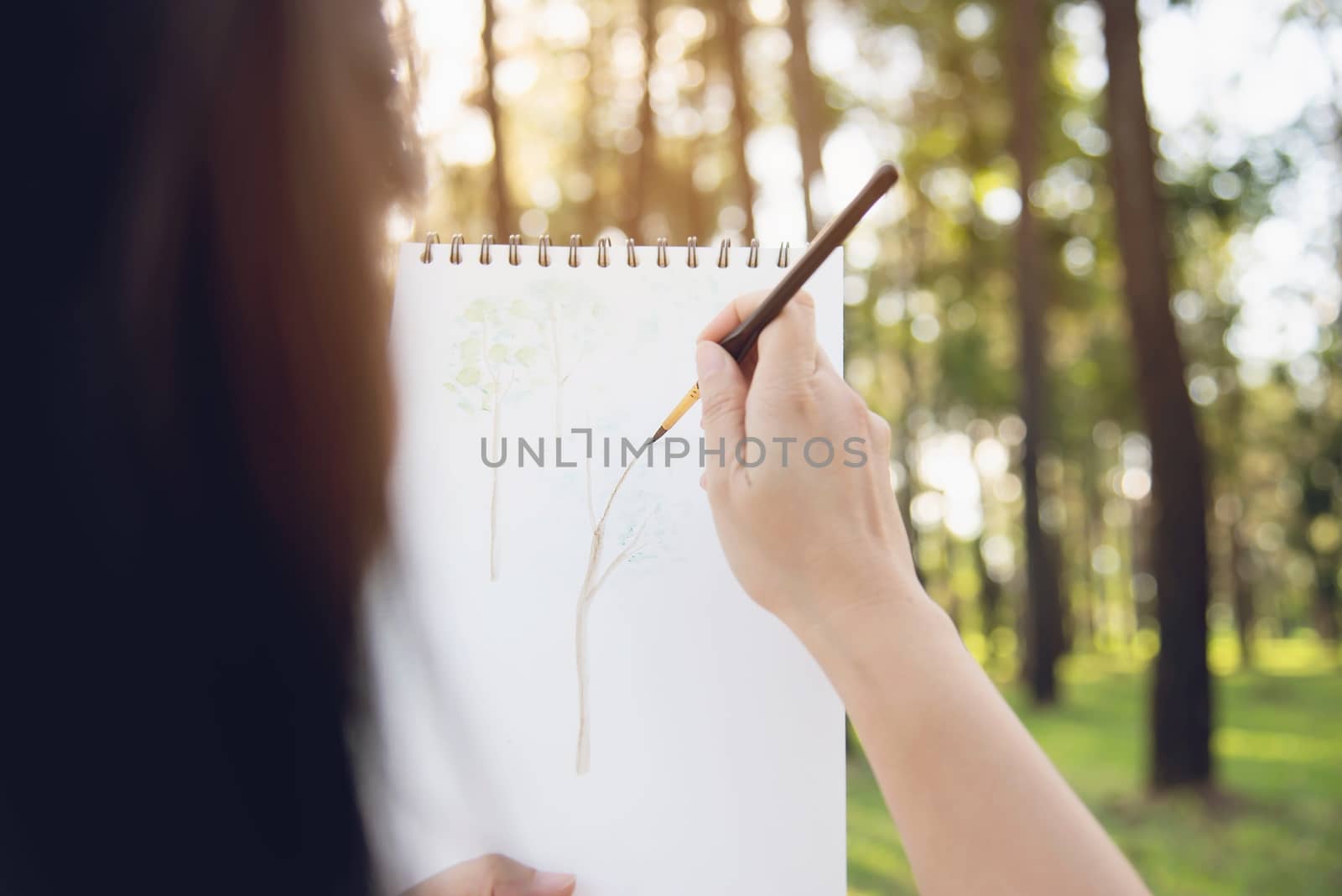 Relax woman painting water colour art work in green garden forest nature - people with creative art in nature stress reduction and meditation concept