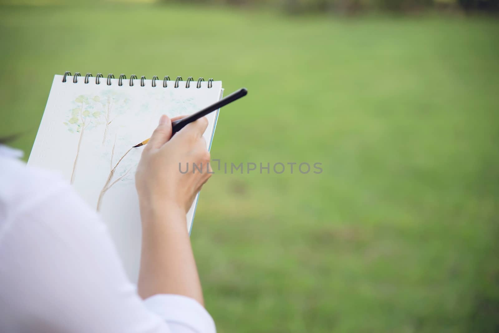 Relax woman painting water colour art work in green garden forest nature - people with creative art in nature stress reduction and meditation concept by pairhandmade