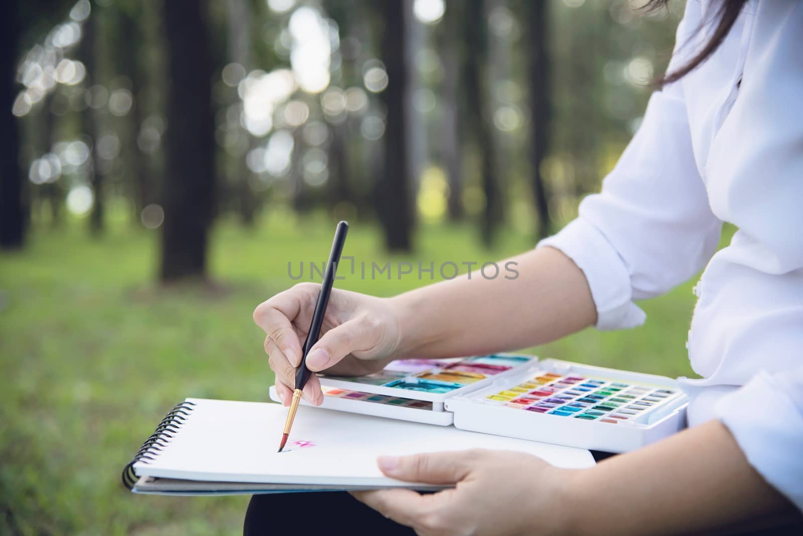 Relax woman painting water colour art work in green garden forest nature - people with creative art in nature stress reduction and meditation concept