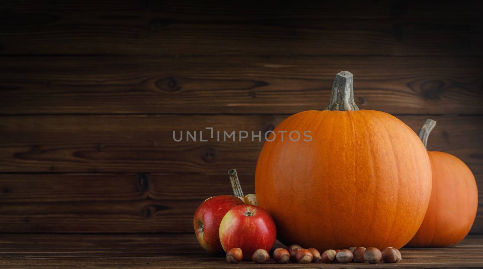 Autumn harvest still life with pumpkins , apples , hazelnuts on wooden background
