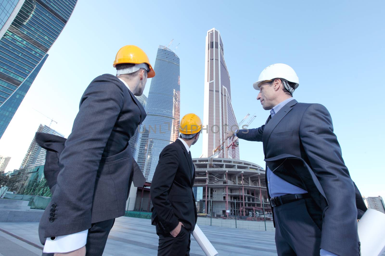 Architects with blueprint at skyscrapers background