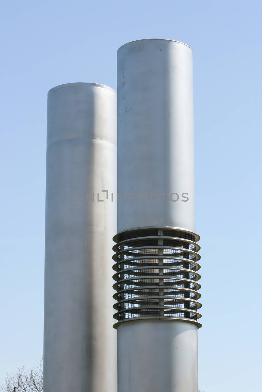 two silver-colored exhaust pipes with blue sky in the background by hadot