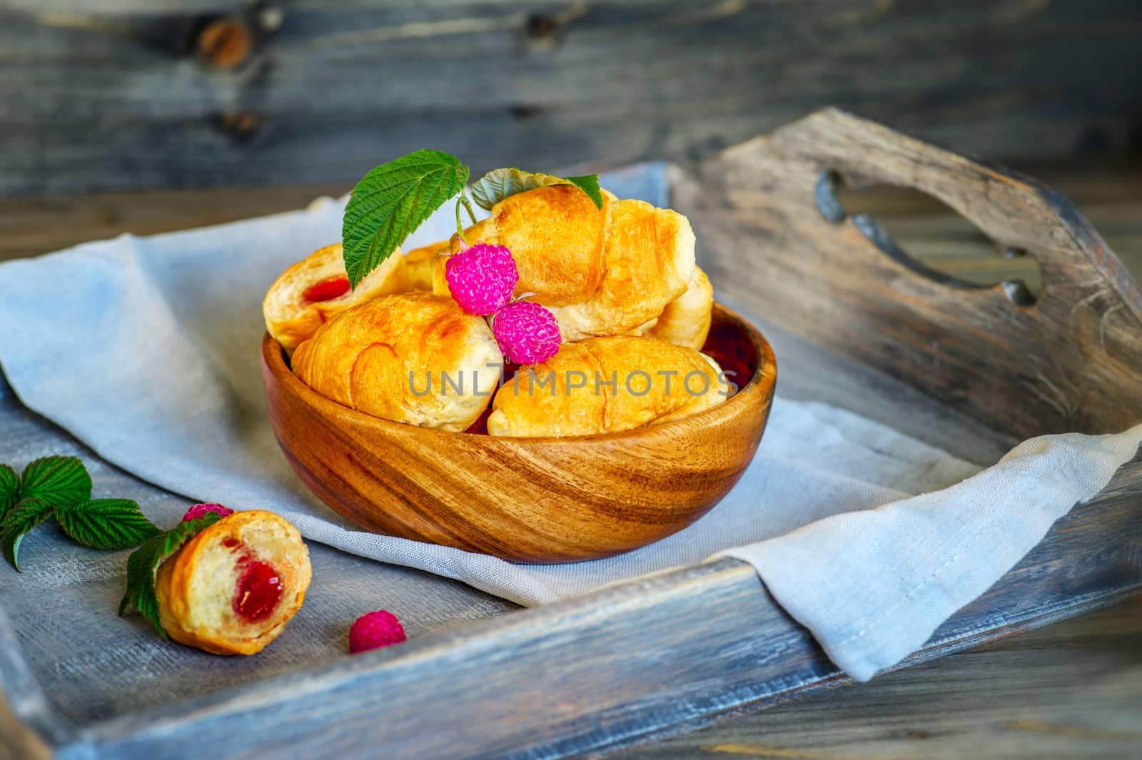 Croissants with raspberries on a wooden tray. The concept of a wholesome breakfast