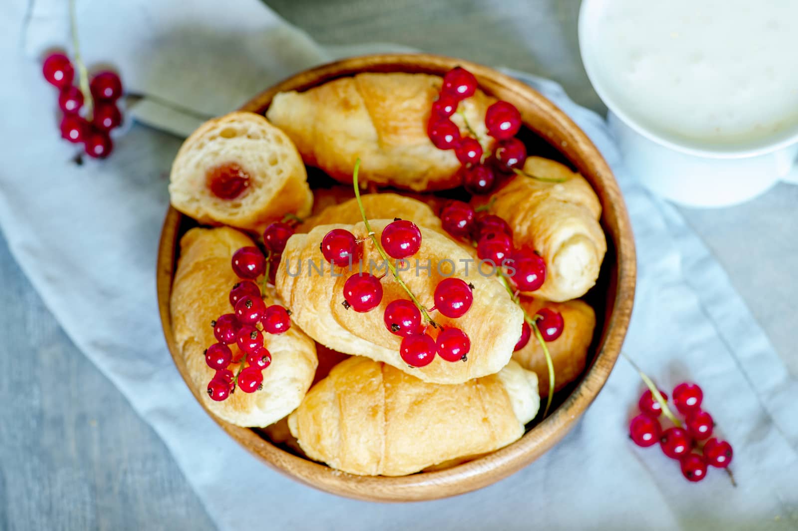 Croissants with currant berries on a wooden tray. The concept of a wholesome breakfast