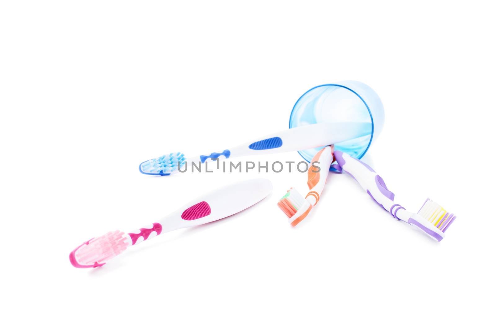 Fallen toothbrush cup holder with scattered toothbrushes, isolated on white background.