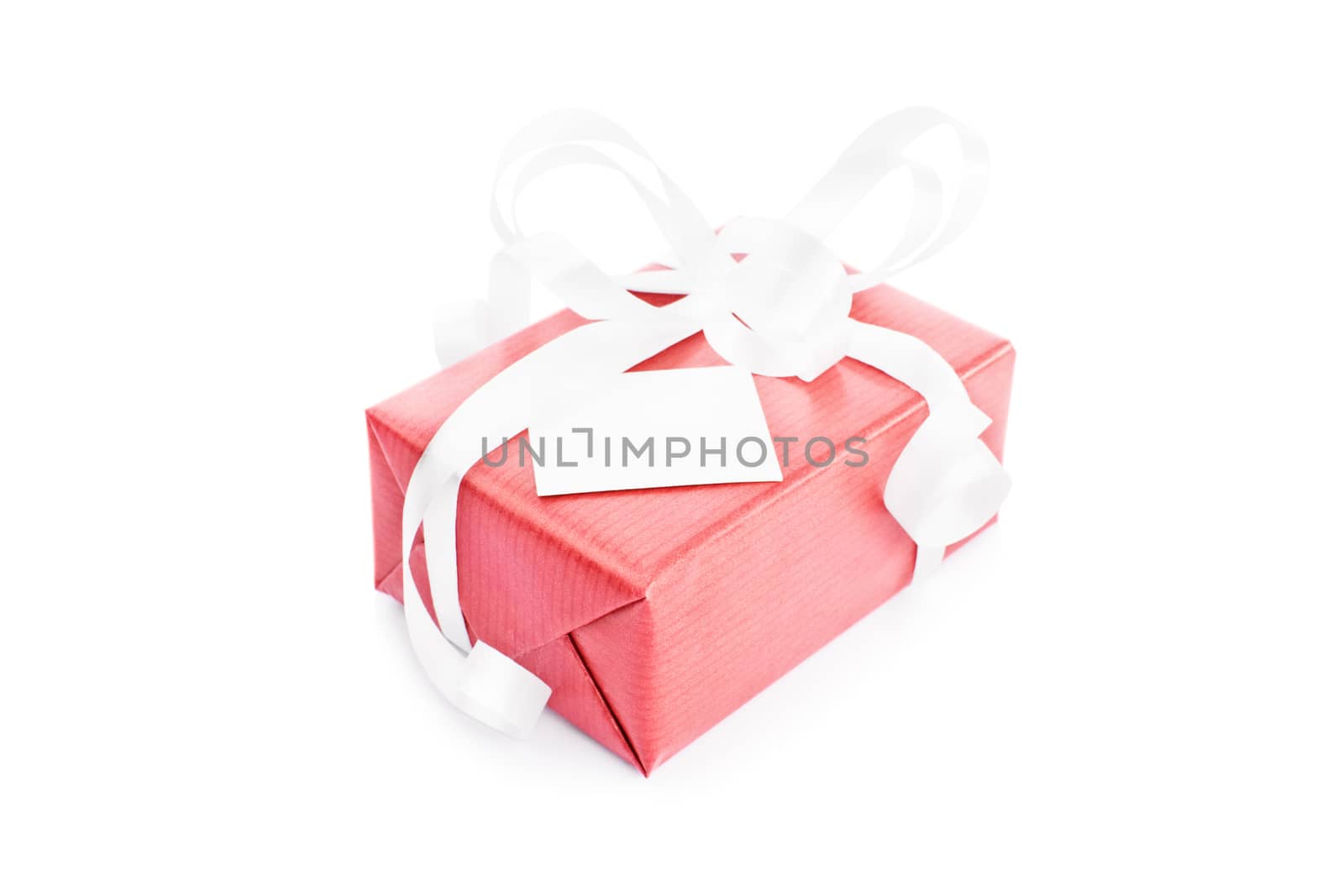 Close-up shot of a red gift box with white ribbons and a greeting card, isolated on white background.