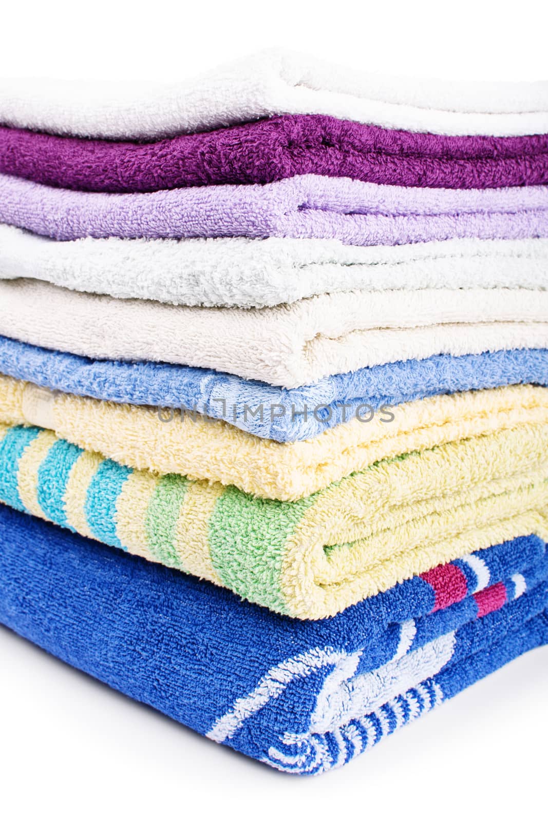 Close up shot of a pile of colorful clean bathroom towels, isolated on white background.