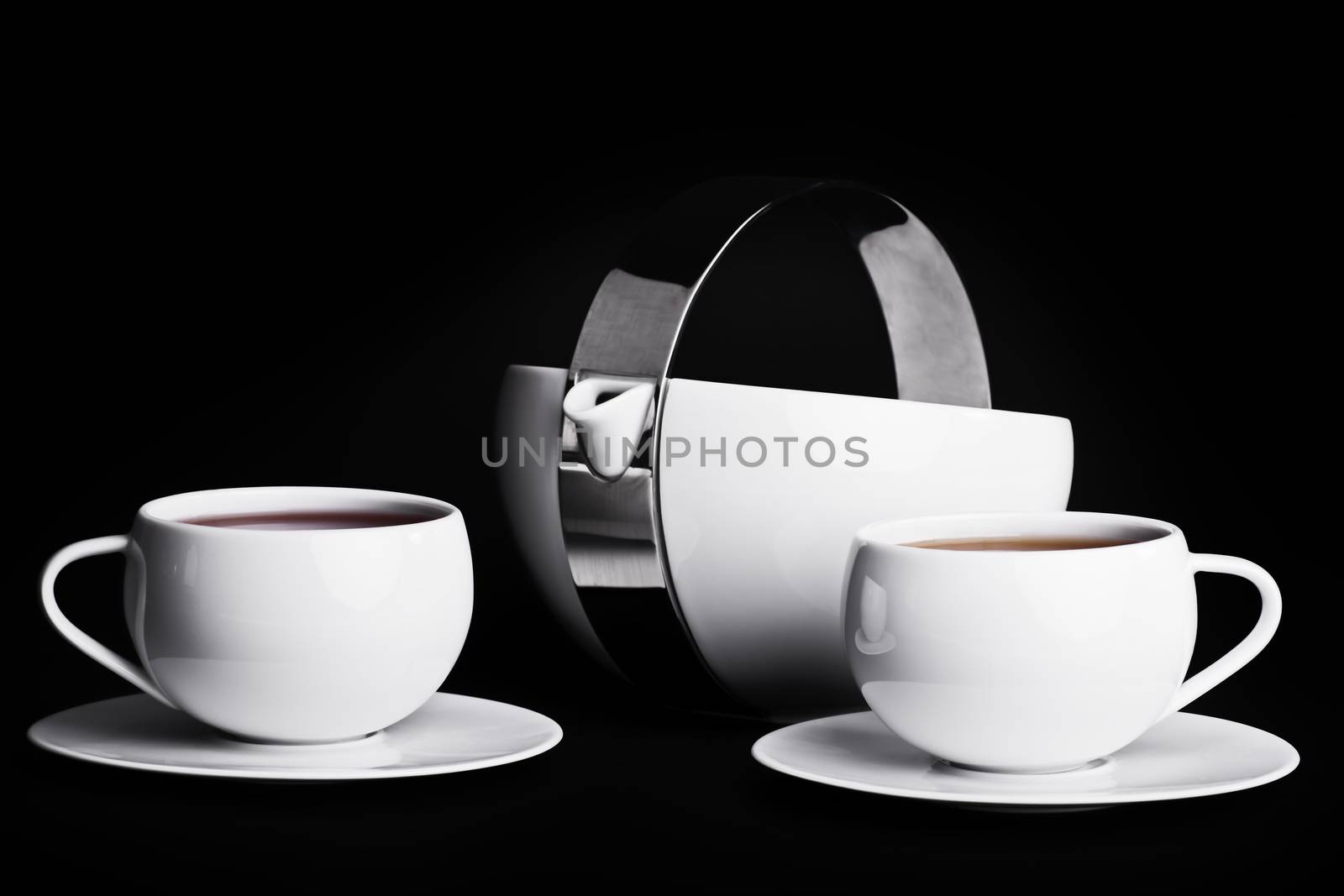 Tea pot with two cups of tea on black background. Low key tea set.