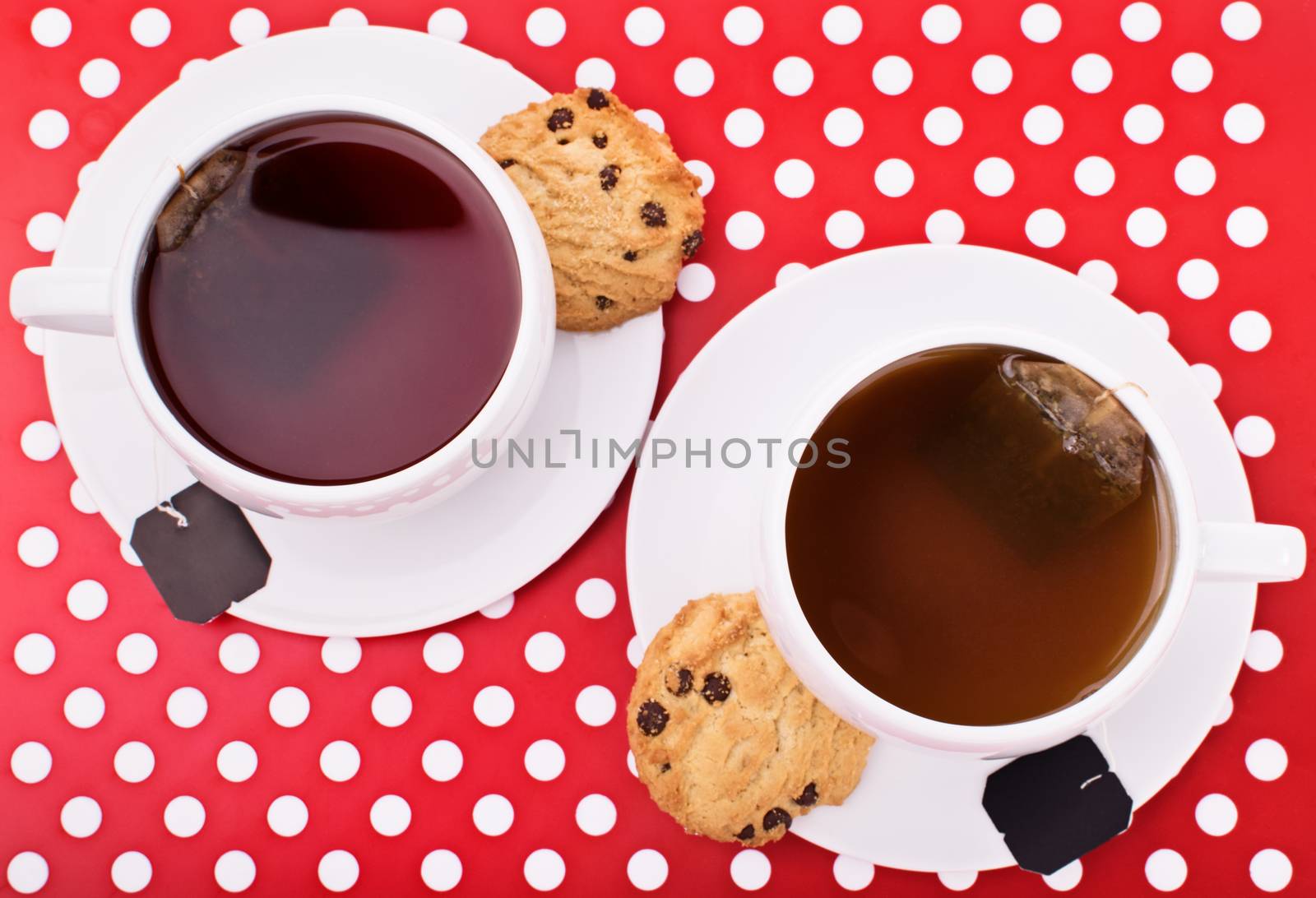 Close-up top view shot of two cups of tea with chocolate chip cookies on a platter.
