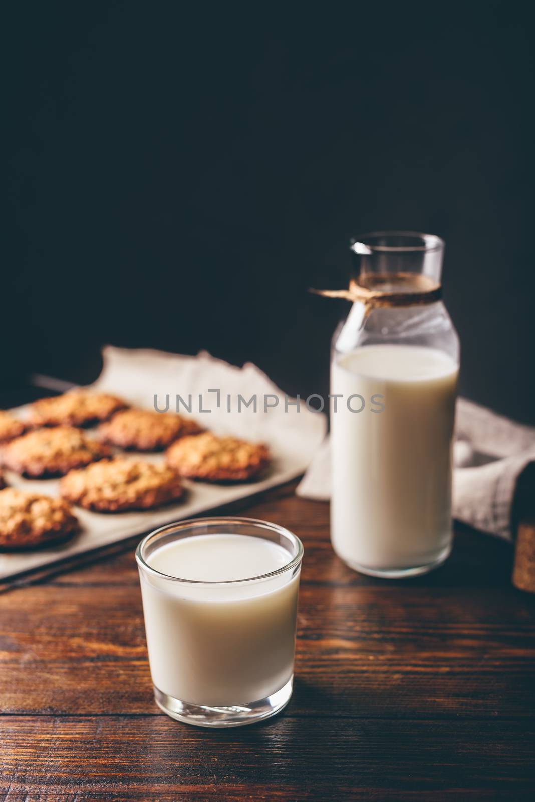 Glass of Milk with Bottle and Oatmeal Cookies on Parchment Paper. Copy Space on the Top.