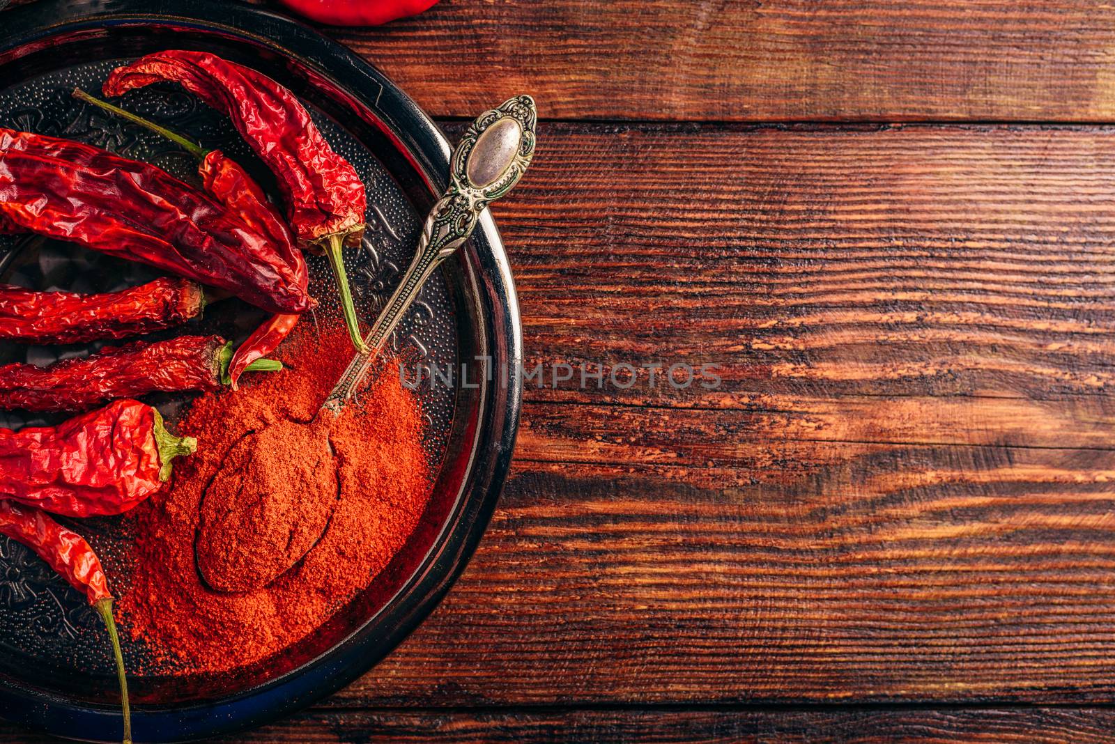 Dried and ground red chili peppers over wooden surface. Copy space