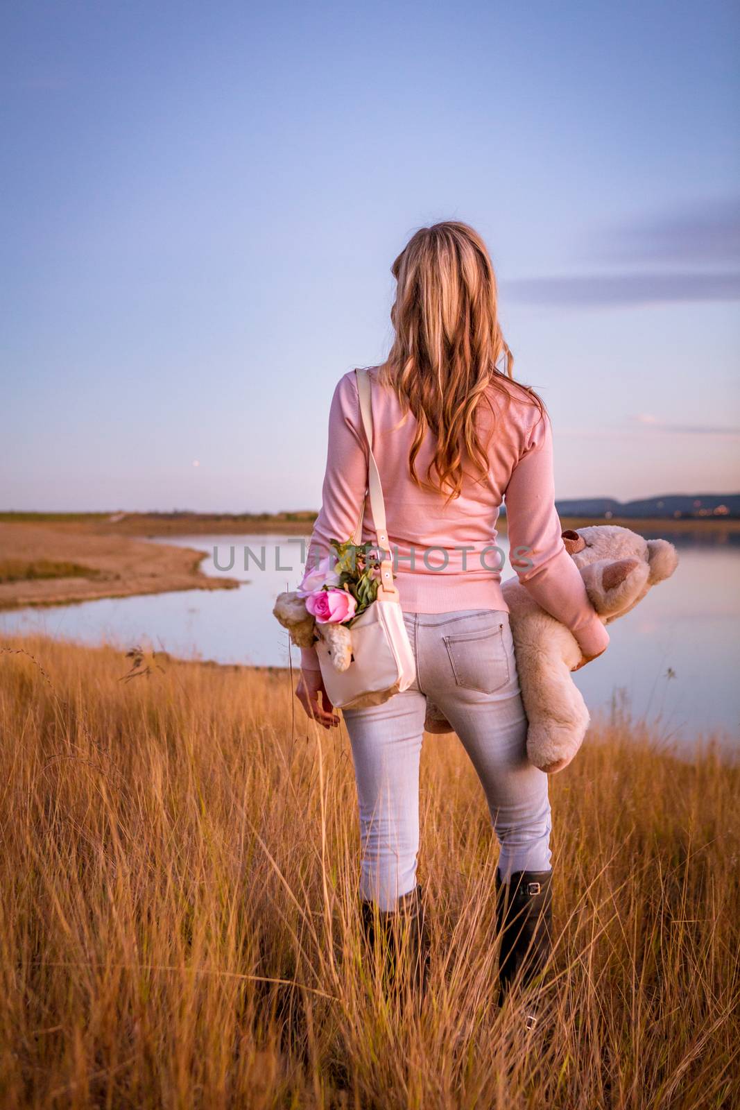 Woman standing in long dry grasses by lake by lovleah