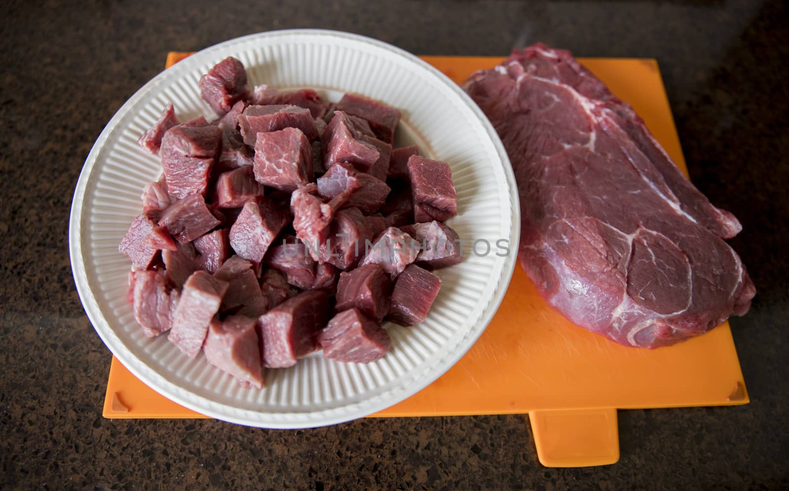 a nice lean piece of beef is cut into pieces in the kitchen to prepare a meat dish