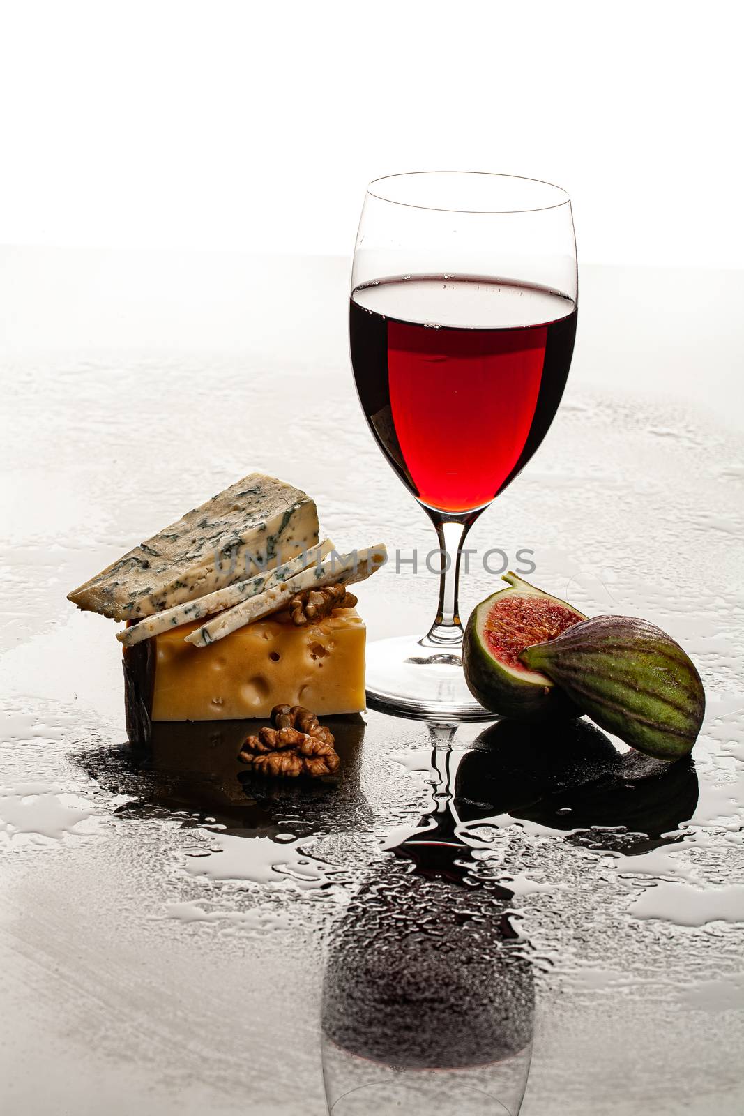 Glass of wine, cheese and fig on a glass background