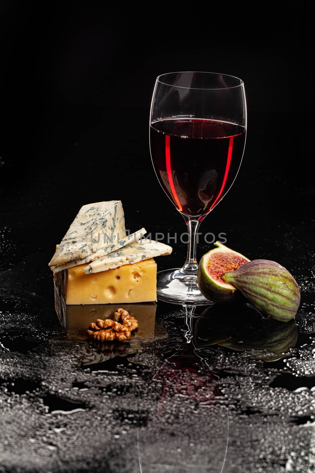 Glass of wine, cheese and fig on a glass background