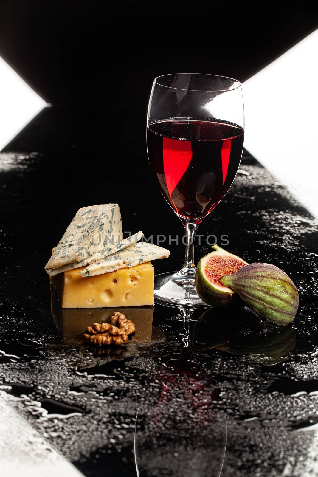 Glass of wine, cheese and fig on a glass background