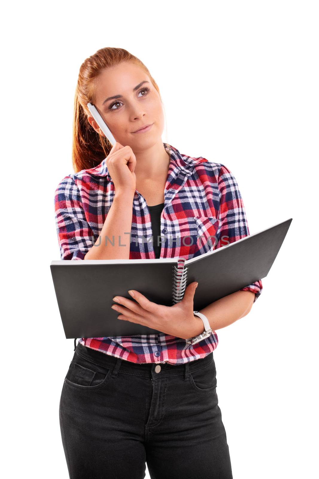 Beautiful young girl in casual clothes holing a notebook in her hand and a pen to her temple thinking, isolated on white background.