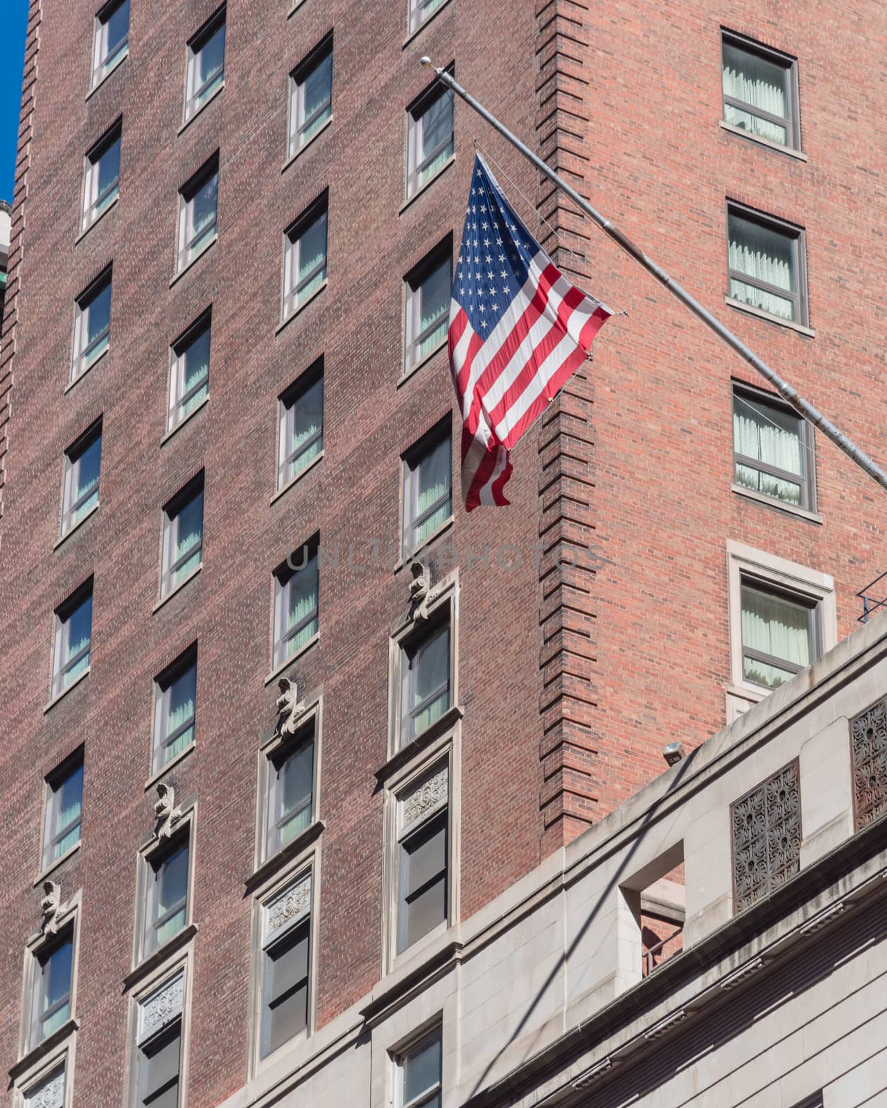 Proudly display of American flag outside of government building near Union Station in downtown Chicago, Illinois. Flying stars and stripes flag with historical brick building facade background