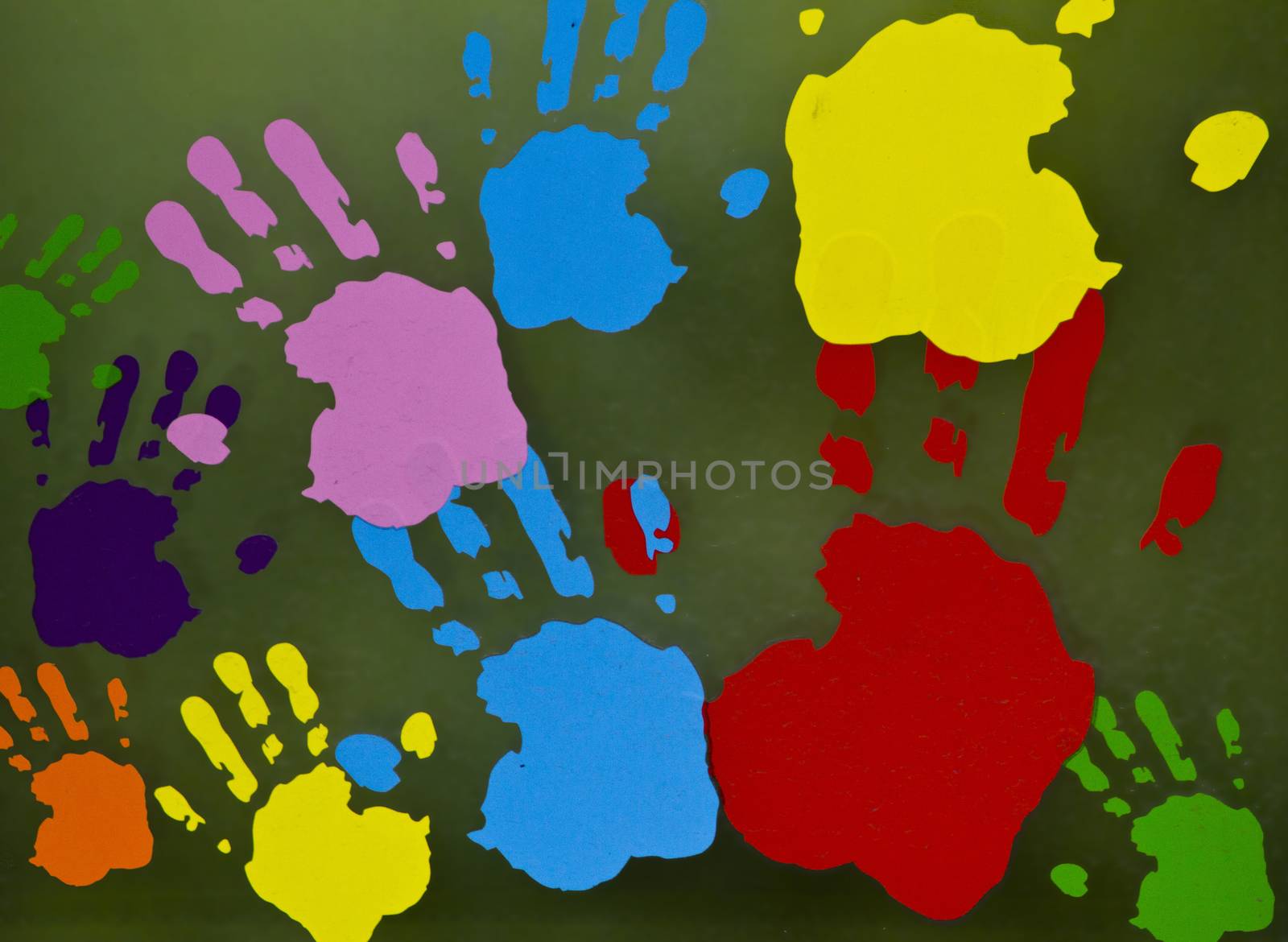 Traces of children's hands of different colors on the surface of a greenish color. by Igor2006