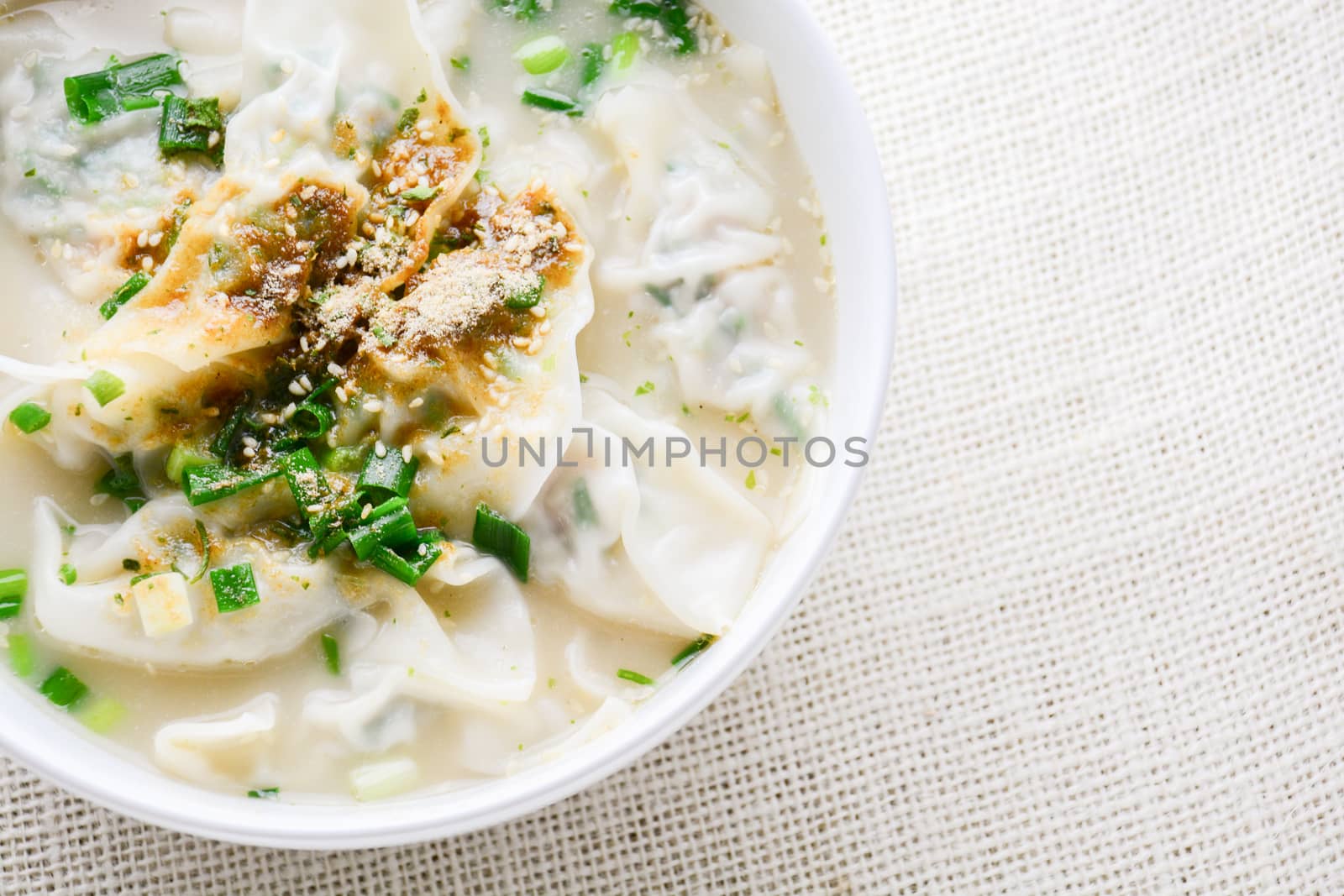 Wonton soup with spring onion served in a white bowl, selective  by yuiyuize