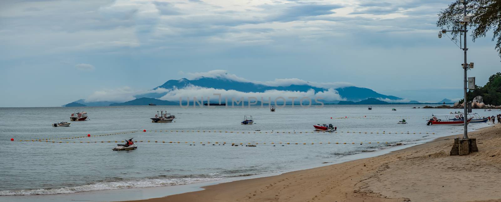 Penang island beach panorama low hanging clouds covering mountains by MXW_Stock