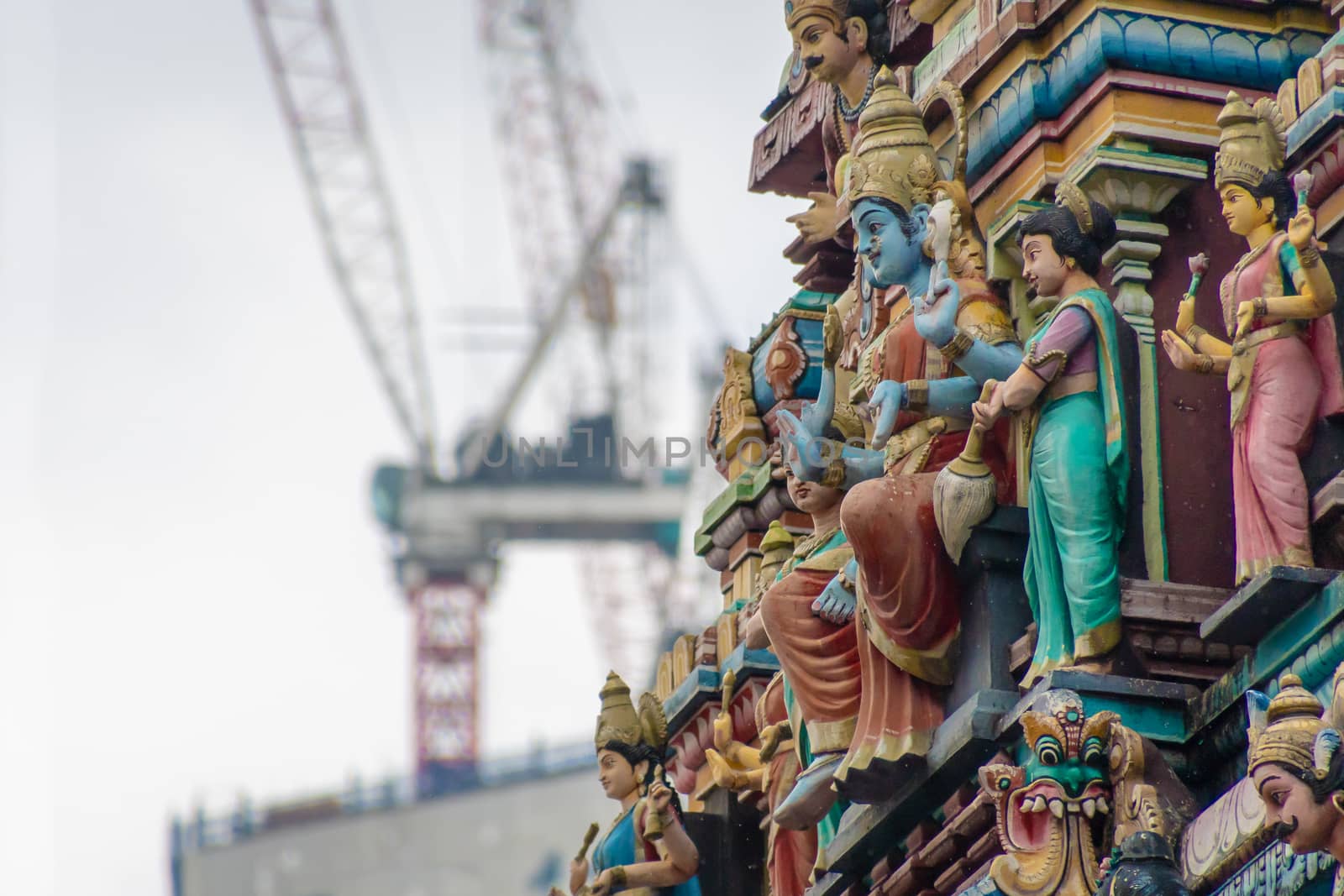 Sri Mahamariamman Temple ornaments of structure in contrast to construction cranes in background in Malaysia