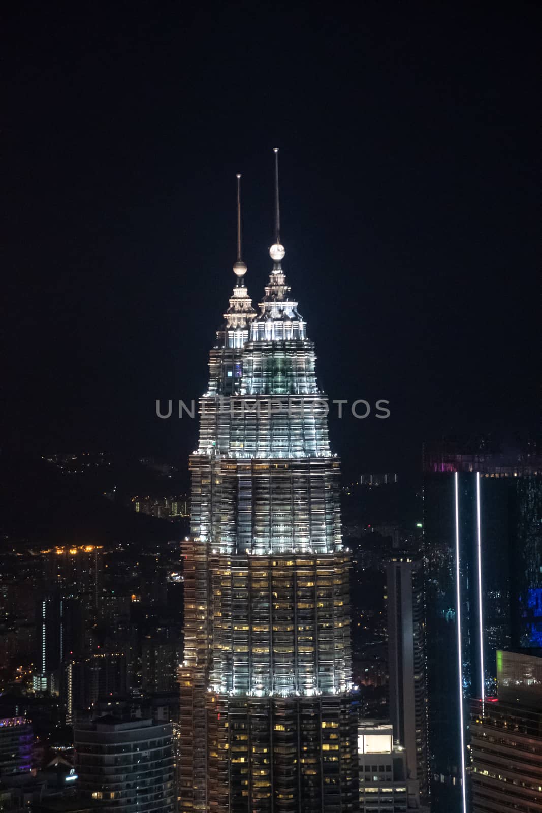 Twin towers in Kuala Lumpur during nigh over viewing illuminated highrise buildings by MXW_Stock