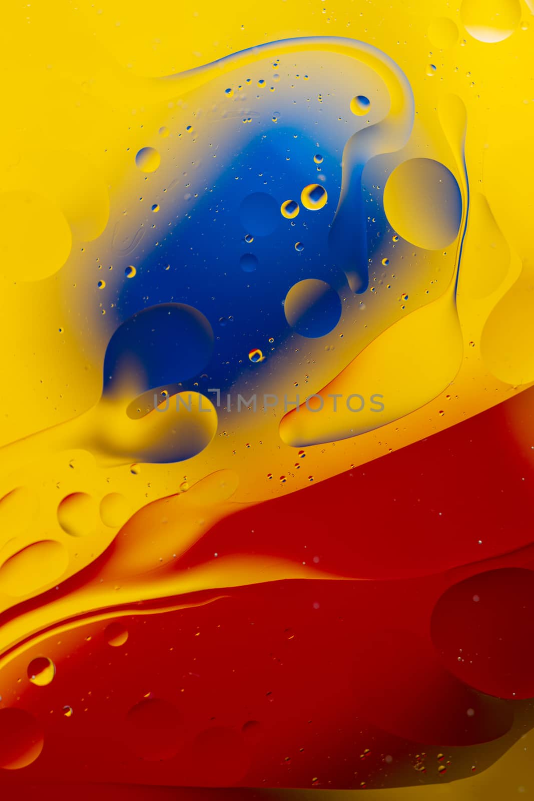 Abstract oil spots in motion on water on blurred yellow backgrou by alexsdriver