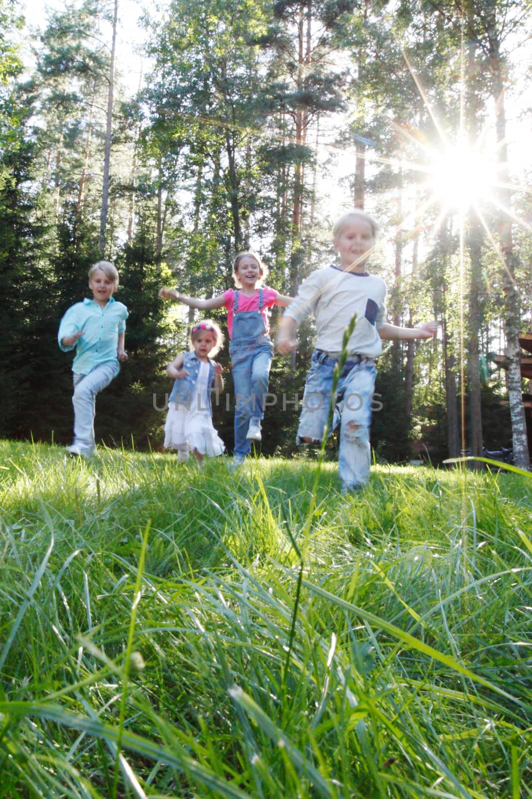 Group of young children running towards camera in park