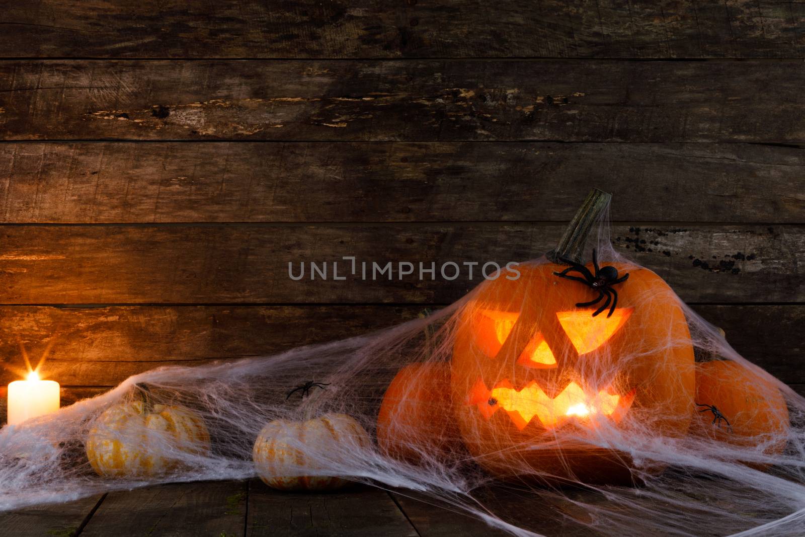 Jack O Lantern Halloween pumpkin, spiders on web and burning candles