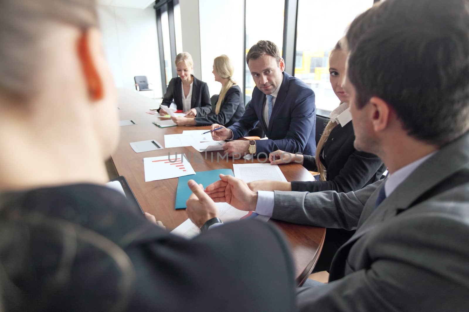 Group of diverse business executives holding a meeting around a table discussing graphs charts showing statistical data analysis