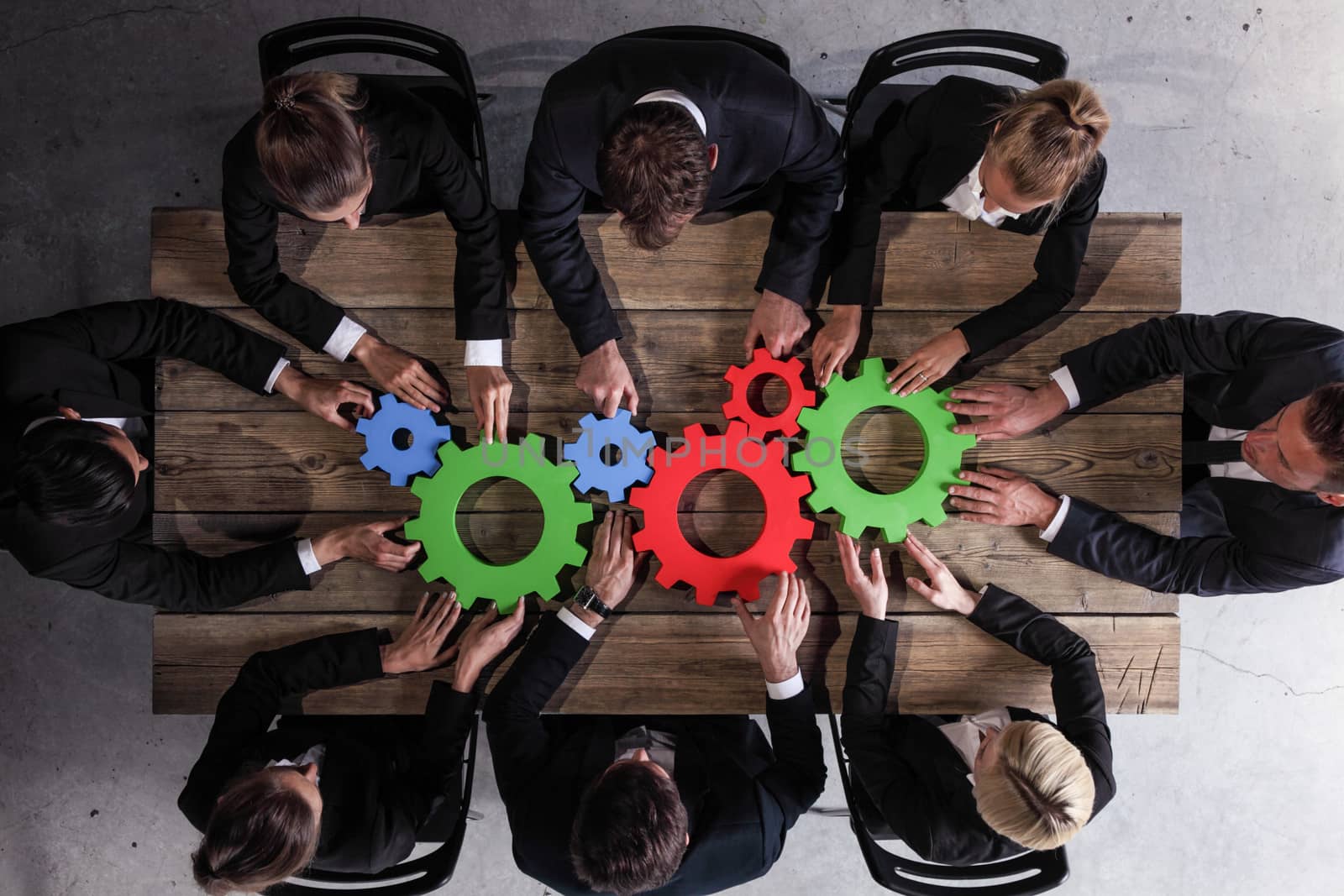 Group Of Business people Joining Together Gears On Table At Workplace