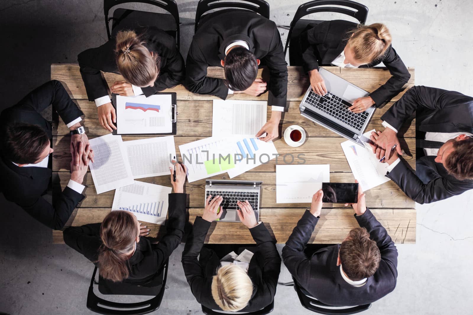 Group of diverse business executives holding a meeting around a table discussing graphs charts showing statistical data analysis