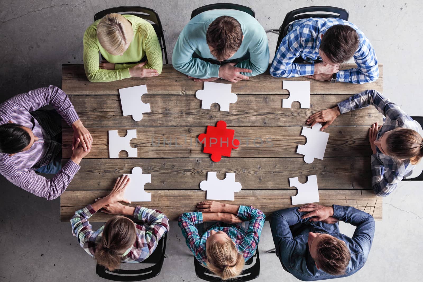 Business people and puzzle on wooden table, teamwork concept