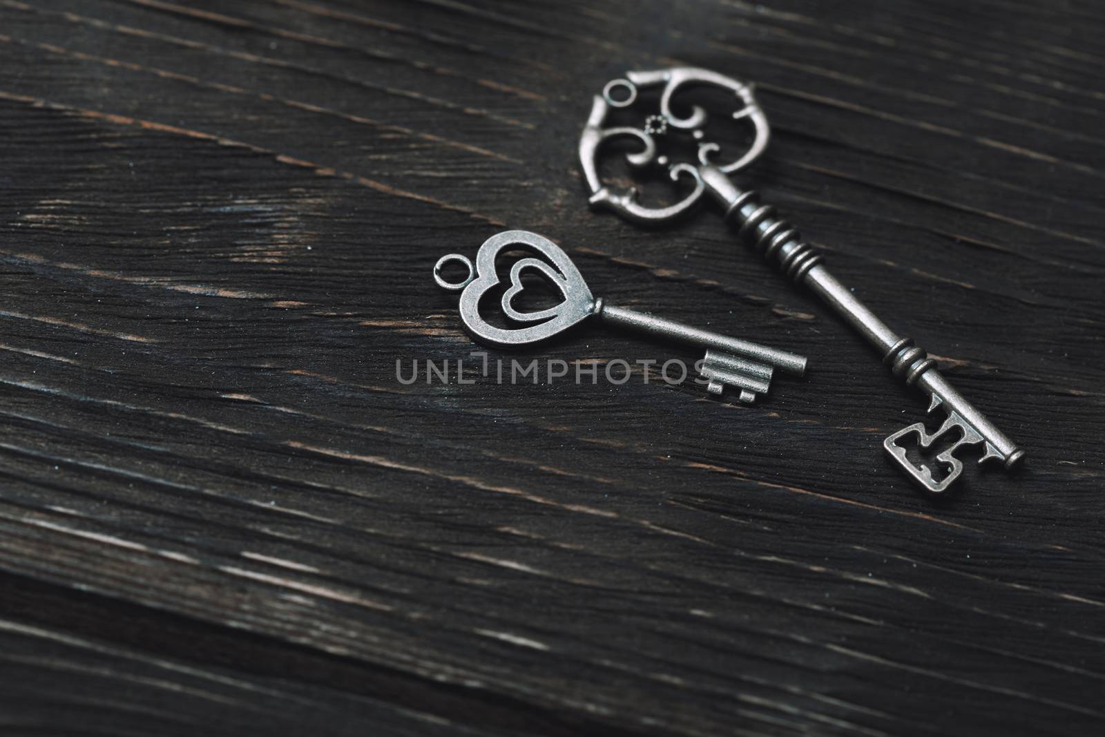 Two vintage bronze keys on a wooden table. Close-up view