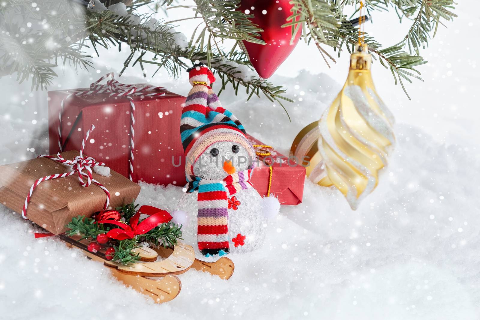 Christmas composition under the Christmas tree - a snowman, boxes with gifts on a sled and other decorations, place for text, copy space.